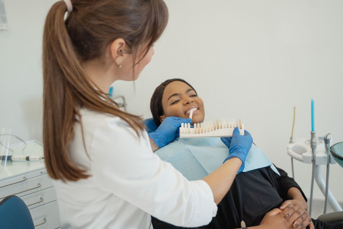 Dentist comparing a tooth shade guide during a teeth whitening Turkey consultation